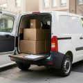 Small white delivery van parked at a curb with parcels loaded in the back