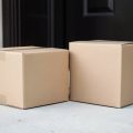 Stack of cardboard shipping parcels on a home doorstep with a paper delivery slip