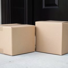 Stack of cardboard shipping parcels on a home doorstep with a paper delivery slip