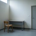 Empty small school room with a single chair and desk facing a blank wall