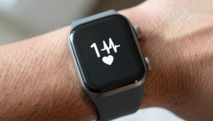 A close-up of a fitness smartwatch on a wrist showing a heart-rate number